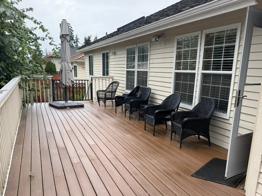 The wide covered deck at the back of the house, with wicker chairs in a row