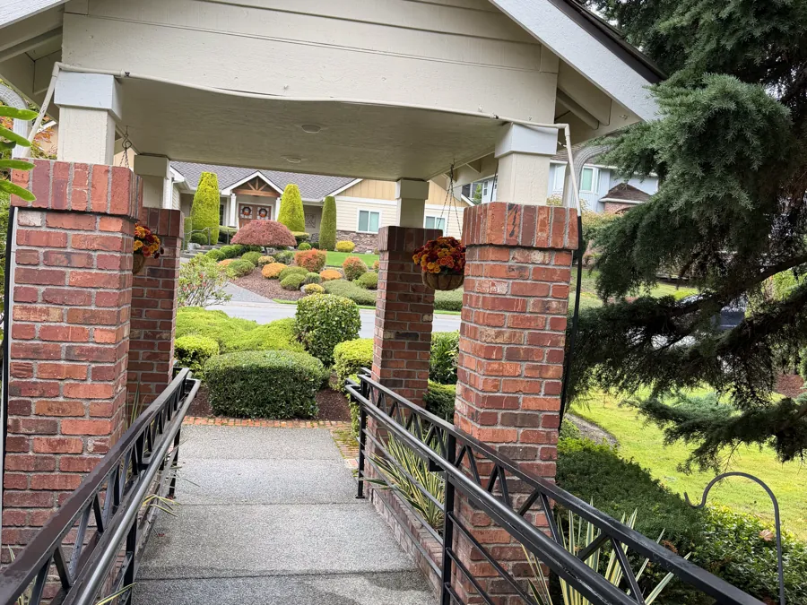 The covered brick entrance with a handrailed, step-free walkway to the front door