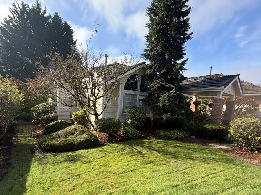 The front lawn and garden beds at Advanced Care Home, with the house behind a tall fir