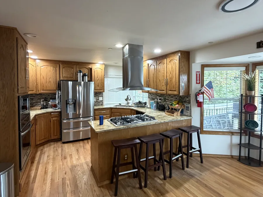 The kitchen with a granite island, bar stools and a gas range