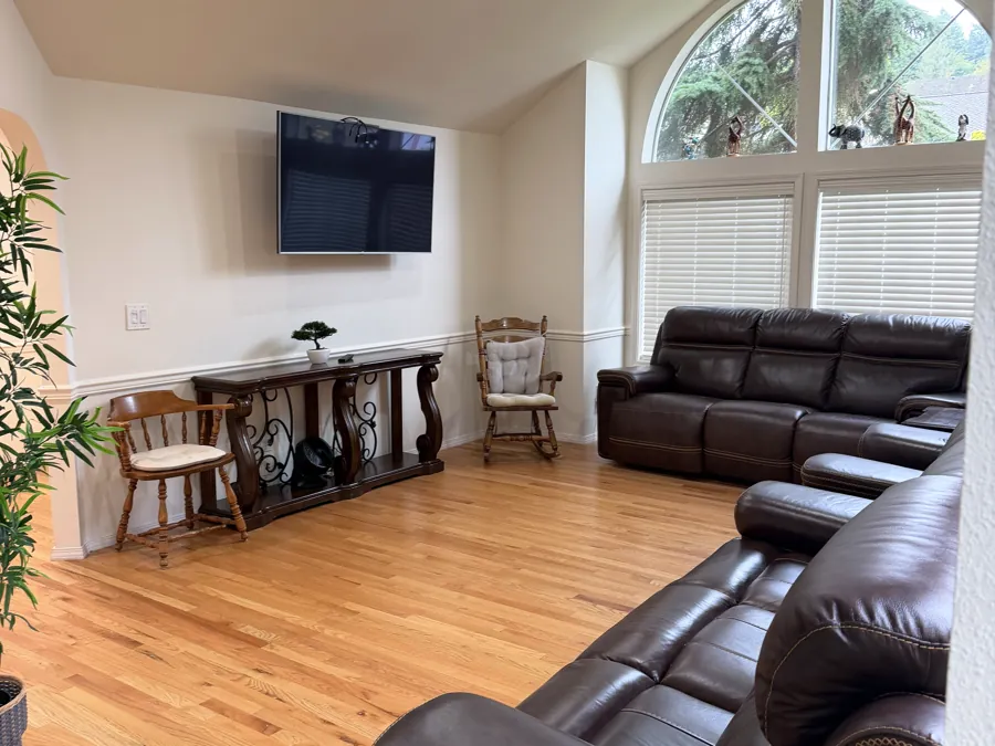 The living room at Advanced Care Home, with leather recliners, hardwood floors and tall arched windows
