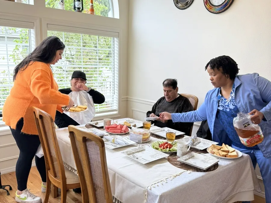 Residents and caregivers around the dining table at lunchtime